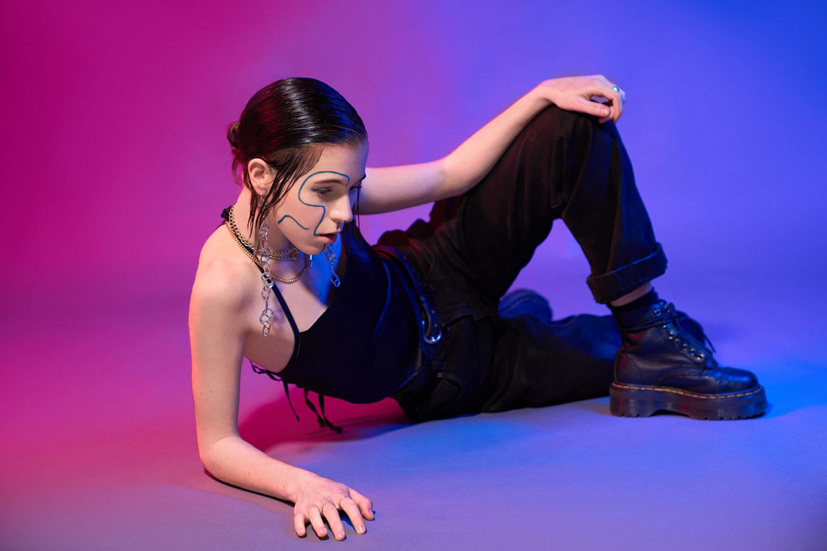 Kreatives Portraitfoto mit Neon-Beleuchtung in Pink und Lila, Model mit künstlerischem Face-Paint und schwarzem Outfit, Fotograf Traunstein