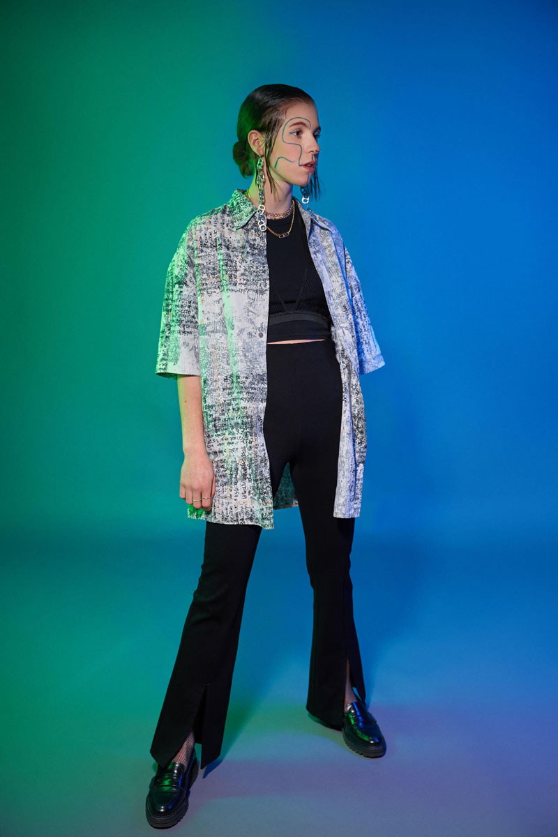 Modefotografie mit grün-blauem Farbverlauf, Model in gemusterter Jacke und schwarzer Hose, professionelle Studiofotografie Traunstein