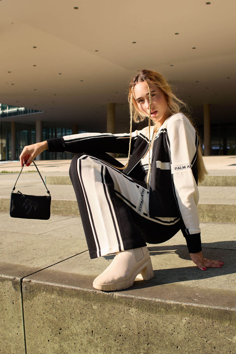 Fashion Model schwarz-weiße Sportbekleidung schwarze Handtasche moderne Architektur Hintergrund