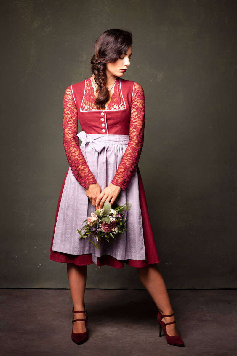 Frau in rotem Dirndl mit Spitzenärmeln hält Blumenstrauß - Trachtenshooting Bayern