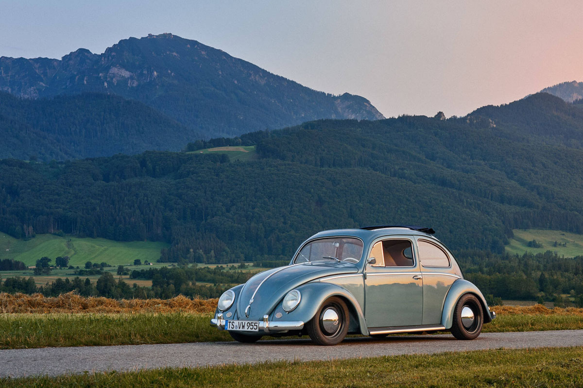 blauer VW Käfer Oldtimer steht bei Sonnenuntergang in Bergen vor den Chiemgauer Alpen