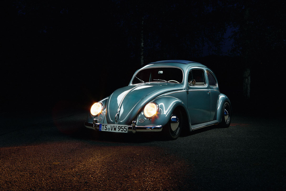 Foto eines blauen VW Käfer von schräg vorne bei Nacht